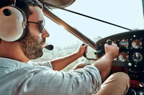 Yong man with beard in an airplane cabin flying a plane Stock Photos