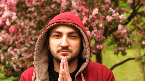 Yonng man keeps palms together and practicing meditation at spring garden Stock Footage 132836382