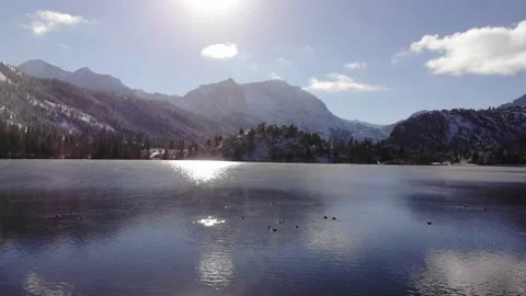 Yosemite Lake with Sun Reflection, Snowy Mountains and Ducks Swimming, Aerial Stock Footage 145474181