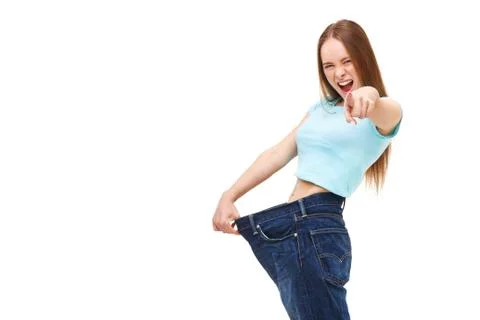 You can do it! Young slim woman with large jeans pointing finger at you - iso Stock Photos