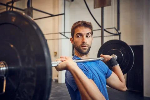 You cant go wrong with strong. a handsome young man lifting weights while Stock Photos
