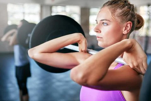 You cant go wrong with strong. a young woman working out with weights at the gym Stock Photos