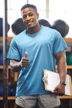 You wont go wrong by joining our gym. Portrait of a muscular young man showing Stock Photos