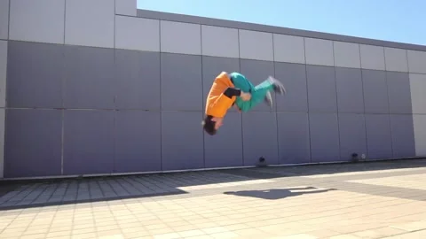 Young acrobatic guy jumping back somersault and dancing break dance outdoors Stock Footage 293839841