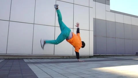 Young acrobatic guy jumping back somersault and dancing break dance outdoors Stock Footage 293839892