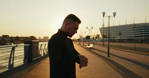 Young active athlete using smartwatch while jogging at sunset on a city street Stock Footage 276546274
