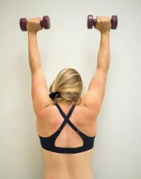 Young active female doing an arm press weights at gym Stock Photos