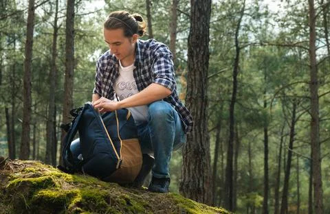 Young active man with backpack at forest during sunny day. Stock Photos