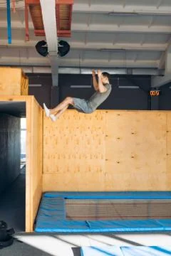 Young active man climbing up on the wall of a gym during a workout Stock Photos