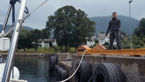 Young active man or sailor holds rope for parking yacht, standing on the dock Stock Footage 91096540