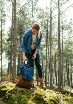 Young active woman with backpack at forest during sunny day. Stock Photos