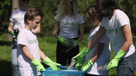Young activists are putting garbage in bags and cleaning green park from Stock Footage 140320842