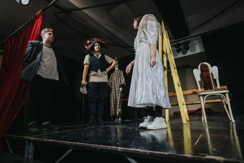 Young actors performing a dramatic play with costumes on stage Stock Photos