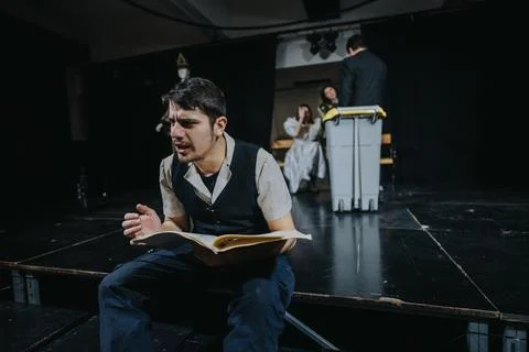 Young actors performing a dramatic scene on a theater stage with expressive Stock Photos