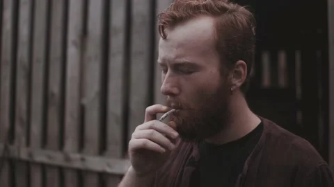 Young addicted man smoke joint and watch around in late fall atmosphere Stock Footage 152943876