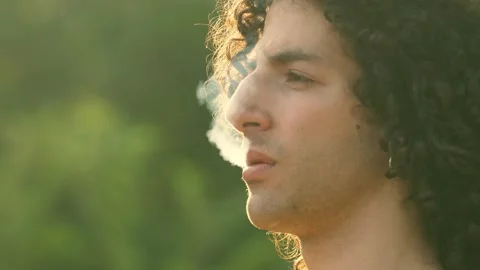 Young addicted man smokes a cigarette looking away thinking Stock Footage 240392014