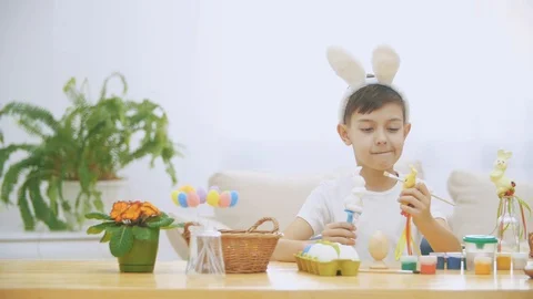 Young adorable boy is sitting at the table full of Easter decorations and is Video stock 104638590