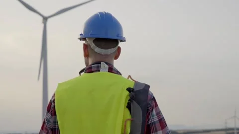 Young adult engineer looking at wind farm. Professional technician with helmet Stock Footage 249287087
