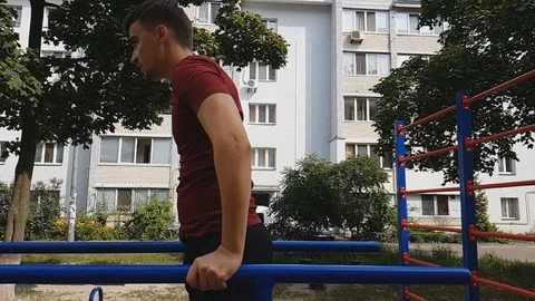 Young adult exercising on parallel bars in neighborhood, slow motion footage Stock Footage 94906975