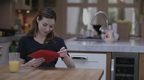 Young adult female opening Valentine's Day Card at Kitchen table Stock Footage