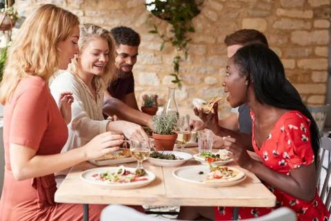 Young adult friends eating lunch at a table in a restaurant Stock Photos