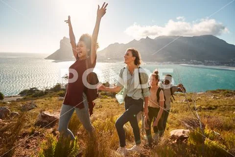 Young adult friends hiking single file uphill celebrate reaching a summit, full Stock Photos