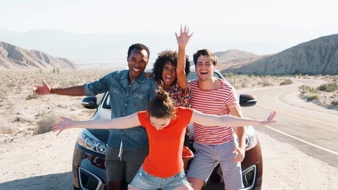 Young adult friends on road trip have fun posing by the car Stock Footage