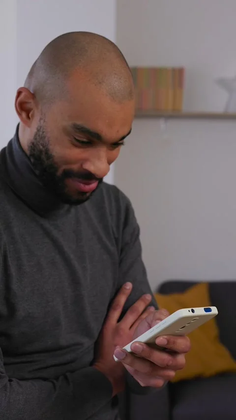 Young adult man reading message on mobile phone at home office Stock Footage 345077662