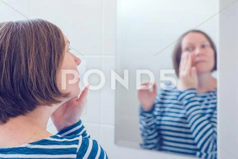 Young adult woman applying anti-aging cream Stock Photos