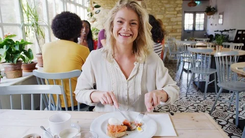 Young adult woman eating brunch, reacting and talking to camera at a restaurant, Stock Footage