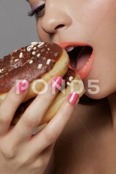 Young Adult Woman Eating Two Doughnuts