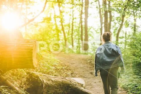 Young adult woman posing at forest trail on sunset Stock Photos