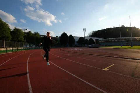 Young adult woman running on a running track Stock Photos