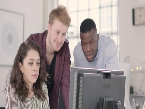 Young adults discussing around a computer in a startup office - track left. Stock Footage 72822726