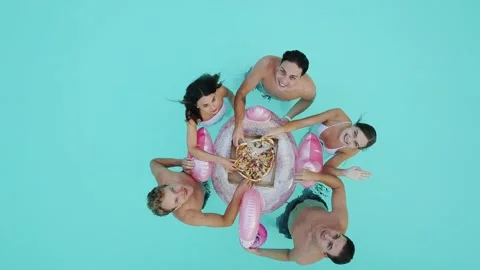 Young adults friends relaxing while eating pizza and drinking cocktail in pool Stock Footage 149606338