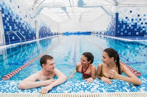 Young adults having fun talking in swimming pool indoors Stock Photos