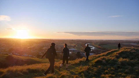 Young adults hiking above a city at sunset, slow motion. Stock Footage