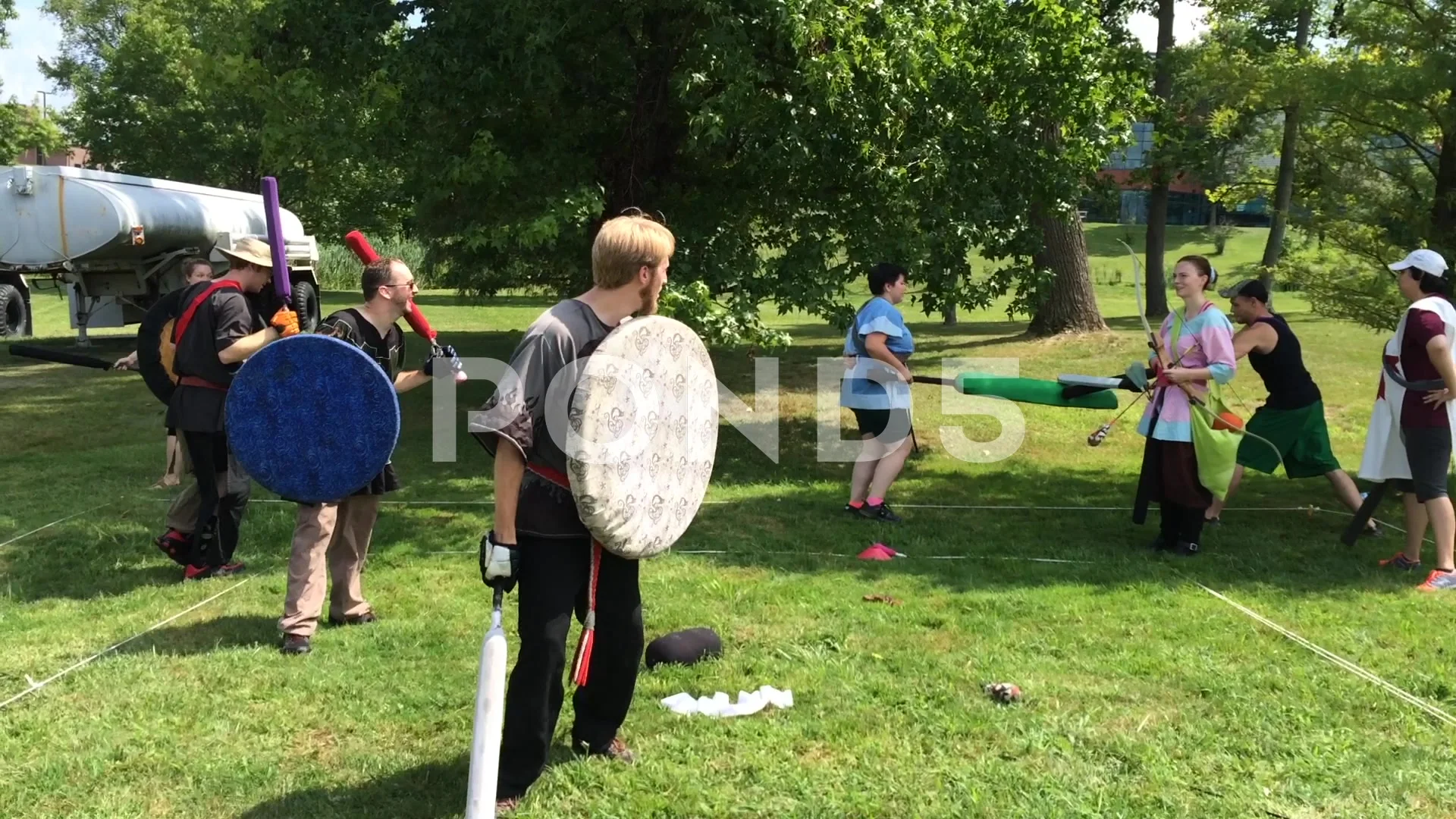 young adults pretend sword fighting on field