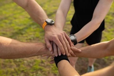 Young adults stacking hands at an outdoor gym bootcamp Stock Photos