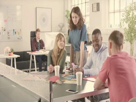 Young adults talking in startup office around a ping pong table - jib down Stock Footage 72865119
