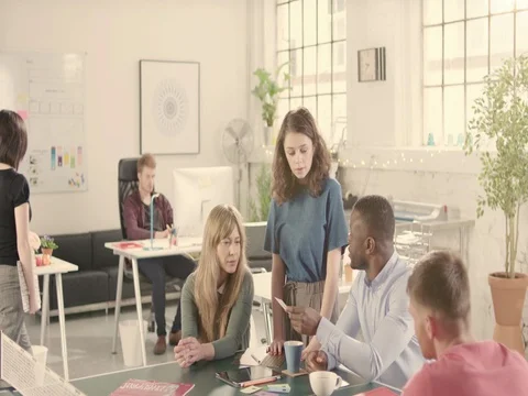 Young adults talking in startup office around a ping pong table - jib down Stock Footage 72865384