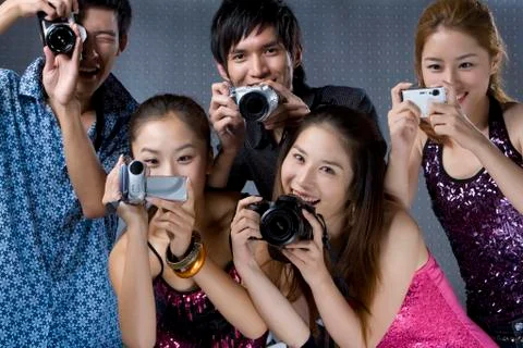 Young adults using digital cameras Stock Photos
