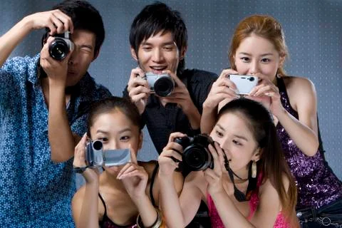 Young adults using digital cameras Stock Photos