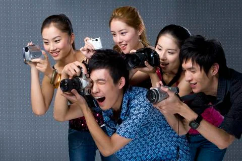 Young adults using digital cameras Stock Photos