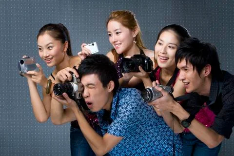 Young adults using digital cameras Stock Photos