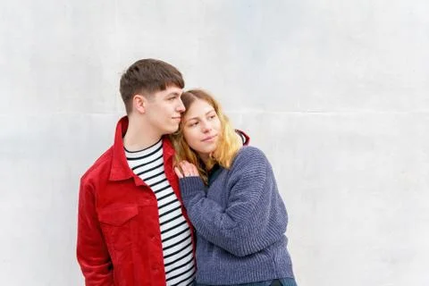 Young affectionate couple standing in front of concrete wall Stock Photos