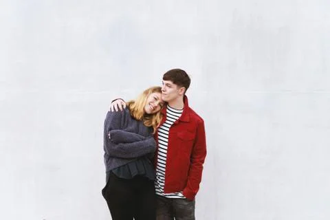 Young affectionate couple standing in front of concrete wall Stock Photos