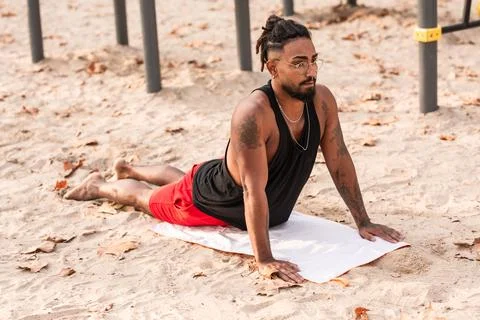 Young African-American athlete, does yoga stretching exercises sun salutation Stock Photos