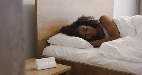 Young African American beautiful woman with curly hair sleeping in the bed early Stock Footage