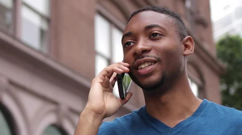 Young African American black man in city talking on cell phone Stock Footage